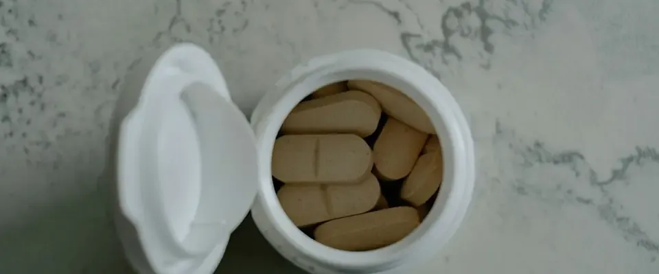 Open bottle of dietary supplement tablets